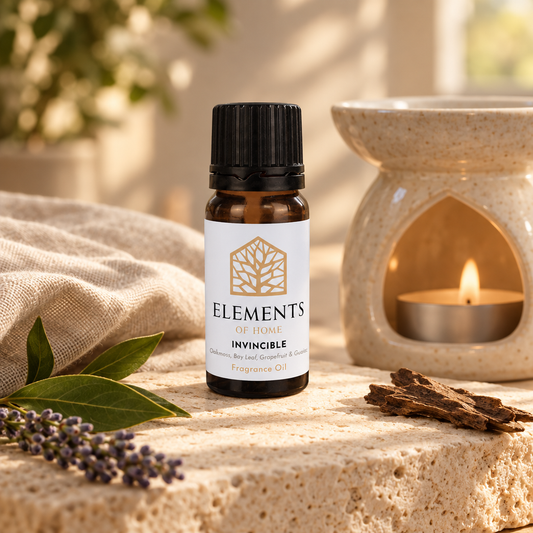 Invincible fragrance oil 10ml bottle beside a lit ceramic oil burner – Elements of Fragrance
