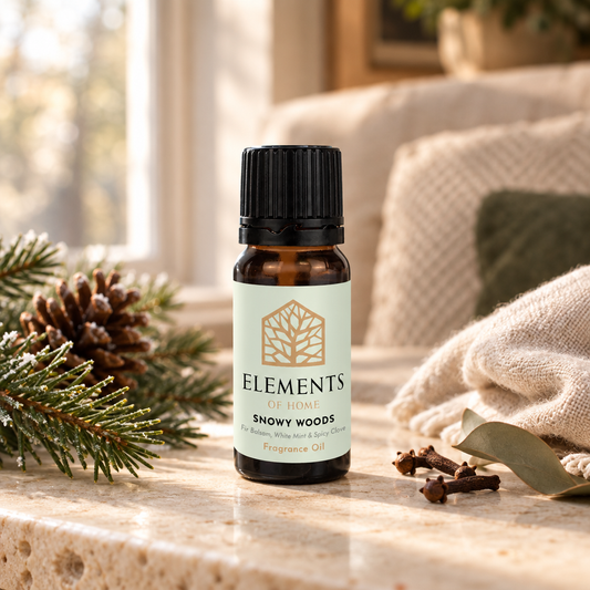 Snowy Woods fragrance oil 10ml bottle beside a lit ceramic oil burner – Elements of Fragrance