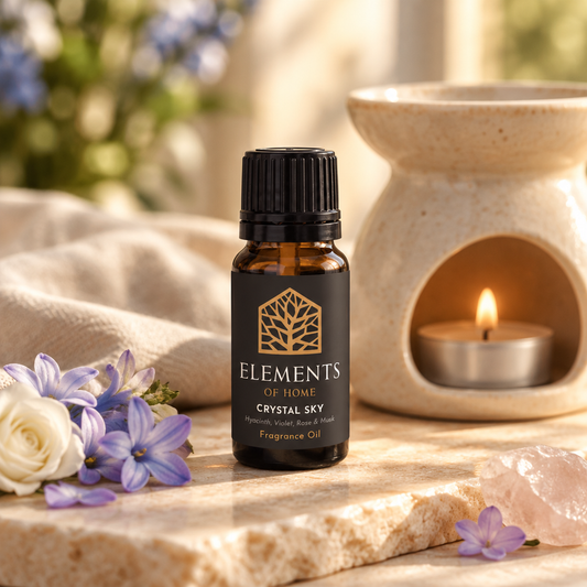 Crystal Sky 10ml fragrance oil beside a lit ceramic oil burner – Elements of Fragrance