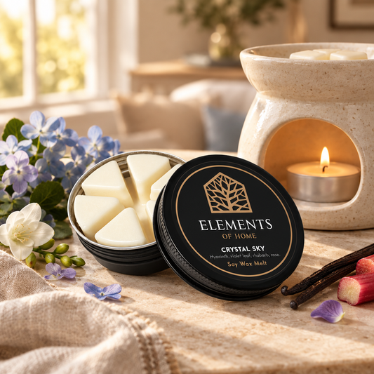 Crystal Sky 50g soy wax melt in a black tin beside a lit ceramic wax burner – Elements of Fragrance