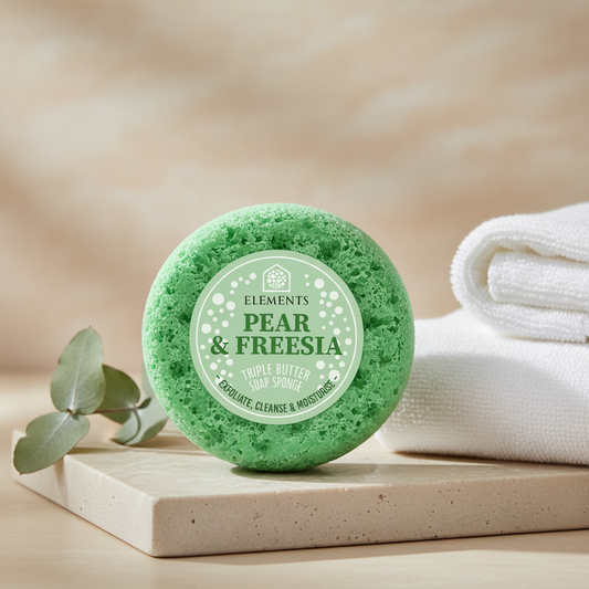 Green English Pear and Freesia Soap Sponge styled on folded towels in a warm bathroom setting
