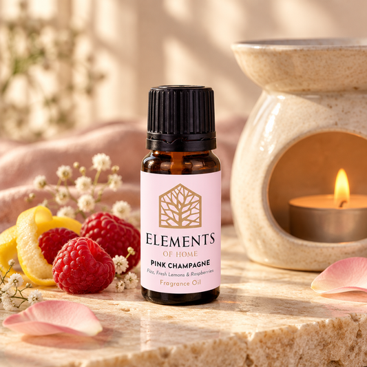Pink Champagne fragrance oil 10ml bottle beside a lit ceramic oil burner – Elements of Fragrance