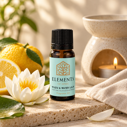 Yuzu & Waterlily fragrance oil 10ml bottle beside a lit ceramic oil burner – Elements of Fragrance
